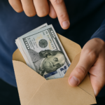 A close-up photorealistic image of a person discreetly handing an envelope filled with cash to another person, suggesting the sensitive and high-risk nature of financial transactions.